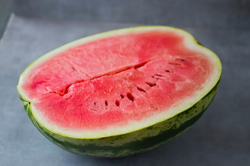 Half ripe watermelon on a gray background.