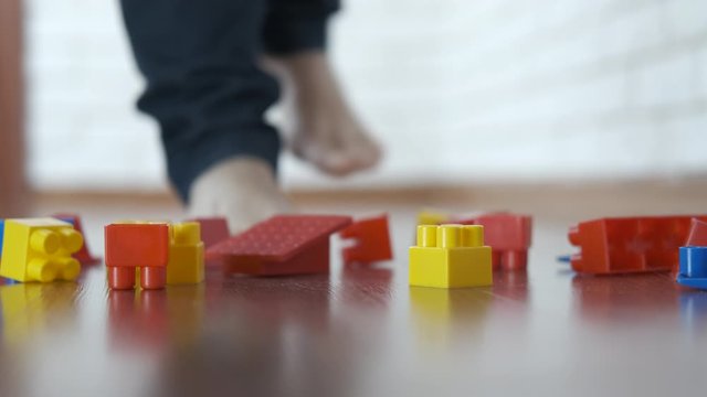 Toys on the floor. Children's toys are scattered on the floor. A woman injures her leg stepping on a children's designer.
