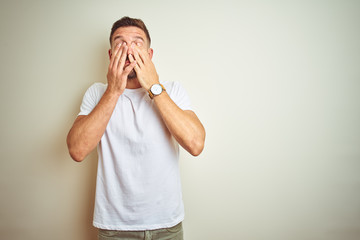 Young handsome man wearing casual white t-shirt over isolated background rubbing eyes for fatigue...