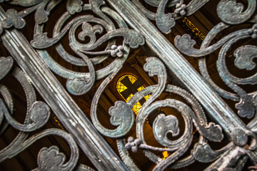 Inside of a mausoleum with a cross seen inside through a metal ornate gate