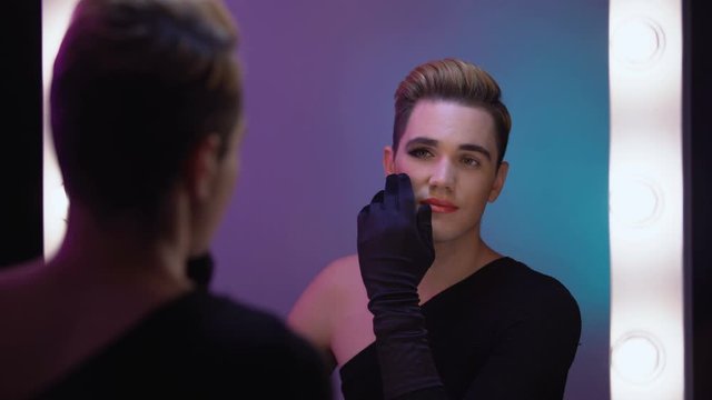 Trans man looking at half-face makeup in mirror, accepting female inner self