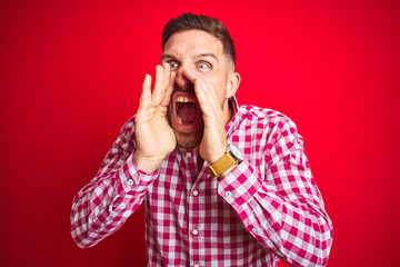 Young handsome man over red isolated background Shouting angry out loud with hands over mouth