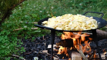 Closeup homemade Cooking delicious fried potatoes in outdoor conditions on fire. Fire fried potatoes.  Simple food. 