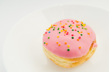 Pink round donut on white plate on white background