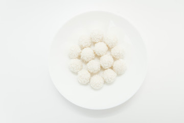 Chocolate covered coconut candies on white plate isolated on white background. Truffle candy set. Selective focus