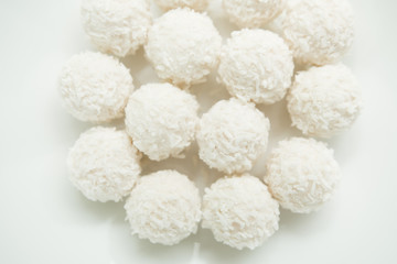 Chocolate covered coconut candies on white plate isolated on white background. Truffle candy set. Selective focus