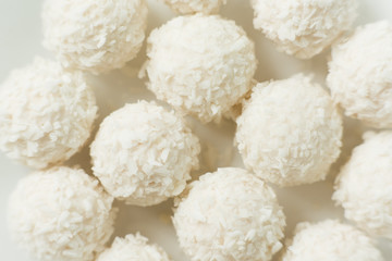 Chocolate covered coconut candies on white plate isolated on white background. Truffle candy set. Selective focus
