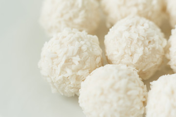 Chocolate covered coconut candies on white plate isolated on white background. Truffle candy set. Selective focus