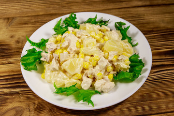 Festive salad with chicken breast, sweet corn, canned pineapple and mayonnaise on wooden table