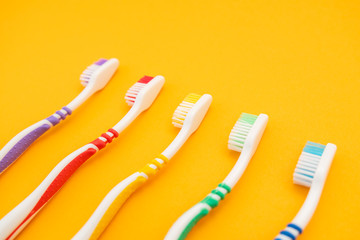set of plastic toothbrushes on yellow background