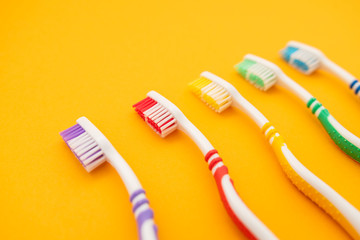 set of plastic toothbrushes on yellow background