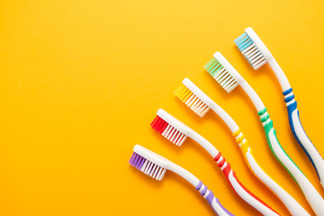 set of plastic toothbrushes on yellow background