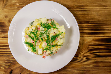 Salad with crab sticks, sweet corn, cucumber, eggs and mayonnaise on wooden table. Top view