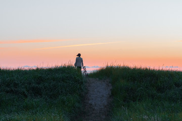 woman walking on wheat field at sunset