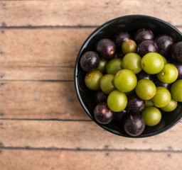 Muscadine grapes are also known as swamp grapes, Florida grapes in a bowl on wood background