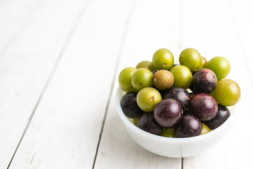 Muscadine grapes are also known as swamp grapes, Florida grapes in a bowl on wood background