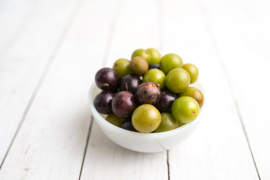 Muscadine grapes are also known as swamp grapes, Florida grapes in a bowl on wood background