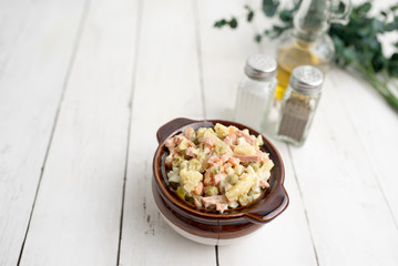 Bowl of traditional Russian salad called Olivie, Russian New Year or Christmas salad on wooden background. Salad from cooked vegetables. Potato salad. 