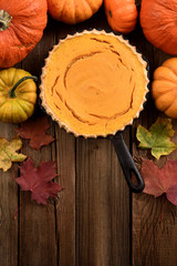 Autumn baking. Open pumpkin pie in cast iron pan on dark wooden background rustic style top view