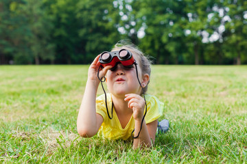 Funny child little girl looking through binoculars on sunny summer day.  Lifestyle, happy...