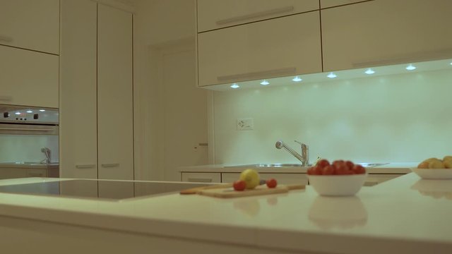 Modern style of kitchen design with flat white cabinet, white kitchen counter top made of quartz with electric cooktop, range and sink. Decorative food and plates are included as a  kitchen design con