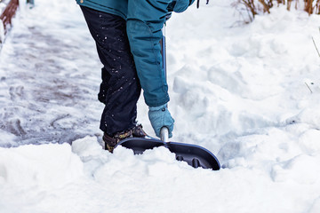 Fototapeta na wymiar A man cleans the snow near the house with a big black shovel.