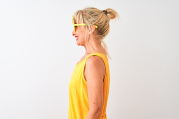Middle age woman on vacation wearing pineapple sunglasses over isolated white background looking to side, relax profile pose with natural face with confident smile.
