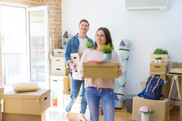 Beautiful young couple smiling in love holding cardboard boxes, happy for moving to a new home