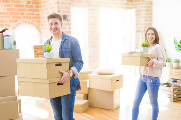 Beautiful young couple smiling in love holding cardboard boxes, happy for moving to a new home