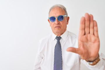 Senior grey-haired businessman wearing tie and sunglasses over isolated white background with open hand doing stop sign with serious and confident expression, defense gesture