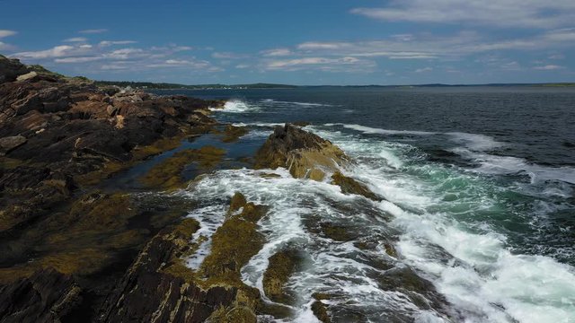 Waves crashing on the seaweed covered rocky shore of Maine Coast STATIONARY AERIAL