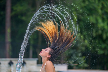 Woman flicking hair to make beautiful frozen water trail on swimming pool