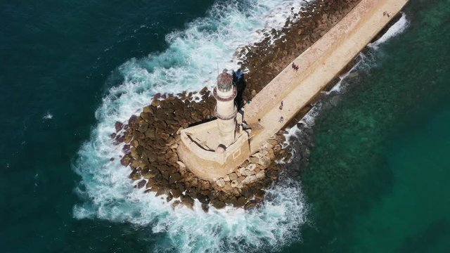 Aerial drone video of iconic Venetian lighthouse in the entrance of picturesque old port of Chania with beautiful colours, Crete island, Greece. Lighthouse in Chania. Lighthouse of the city of Chania.