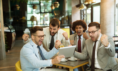 Four male friends are watching game drinking beer at the pub.