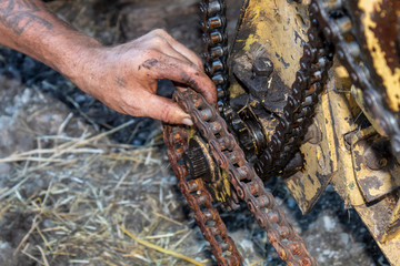 Man Hand Trying to Put Chain on Sprocket Wheel While Repairing Forage Harvester