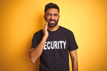 Arab indian hispanic safeguard man wearing security uniform over isolated yellow background touching mouth with hand with painful expression because of toothache or dental illness on teeth. 