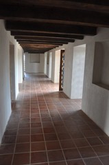 Corridor with white walls, doorways, wooden ceiling, tiled floor and stained glass in window