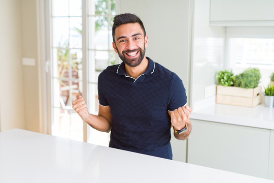 Handsome hispanic man at home celebrating surprised and amazed for success with arms raised and open eyes. Winner concept.