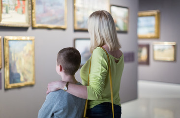 Mother and son looking at paintings in halls of museum