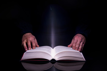 Person reading book with glowing light coming from inside of it. High resolutin image.