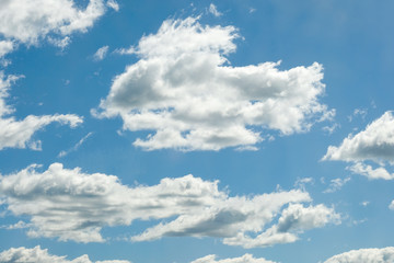Naklejka na ściany i meble White clouds on a blue sky on a sunny summer day.