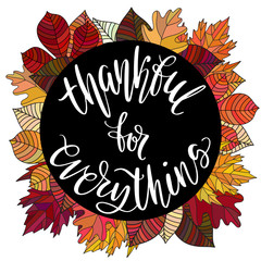 Thankful for everything hand written words in black circle on autumn leaves background.