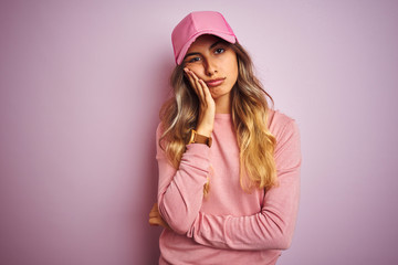 Young beautiful woman wearing cap over pink isolated background thinking looking tired and bored with depression problems with crossed arms.