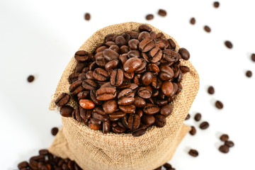 Coffee beans. Jute burlack sack with roasted coffee beans and some dropped beans, isolated on white background.