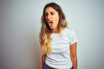 Young beautiful woman wearing casual white t-shirt over isolated background angry and mad screaming frustrated and furious, shouting with anger. Rage and aggressive concept.