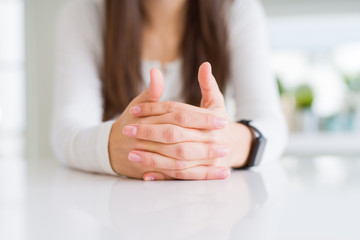 Close up of woman crossed hands over white table