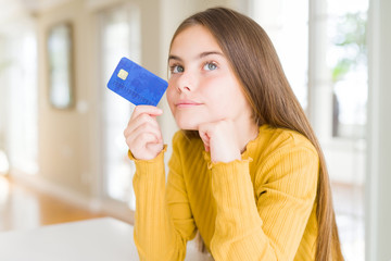 Beautiful young girl kid holding credit card serious face thinking about question, very confused...