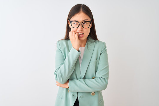 Chinese businesswoman wearing elegant jacket and glasses over isolated white background looking stressed and nervous with hands on mouth biting nails. Anxiety problem.