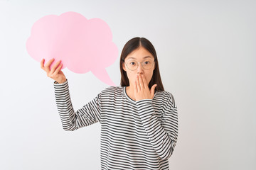 Young chinese woman holding cloud speech bubble over isolated white background cover mouth with hand shocked with shame for mistake, expression of fear, scared in silence, secret concept