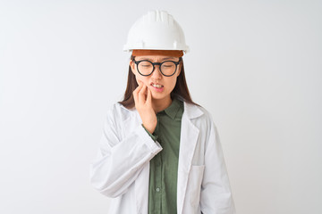 Young chinese engineer woman wearing coat helmet glasses over isolated white background touching mouth with hand with painful expression because of toothache or dental illness on teeth. 